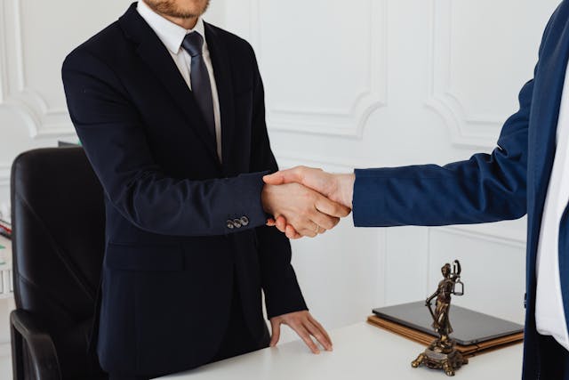 a person with a lawyer, discussing with insurance company representatives.