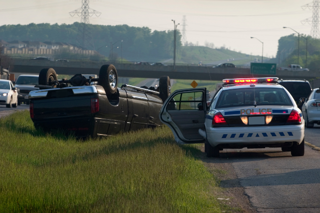 Police unit at scene of accident. Car flipped over.