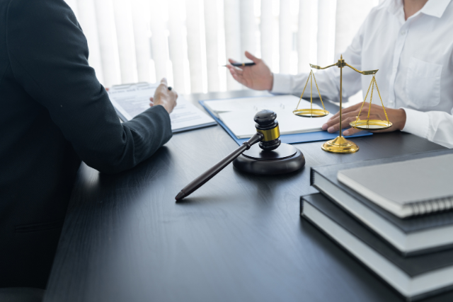 a person sitting at a table with a lawyer, discussing with insurance company representatives.